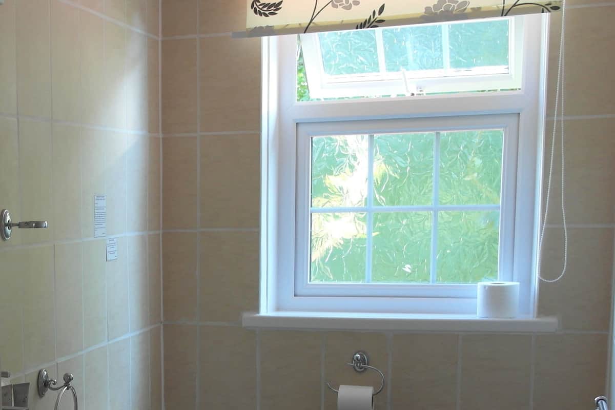 A bathroom with a toilet, sink, and window.