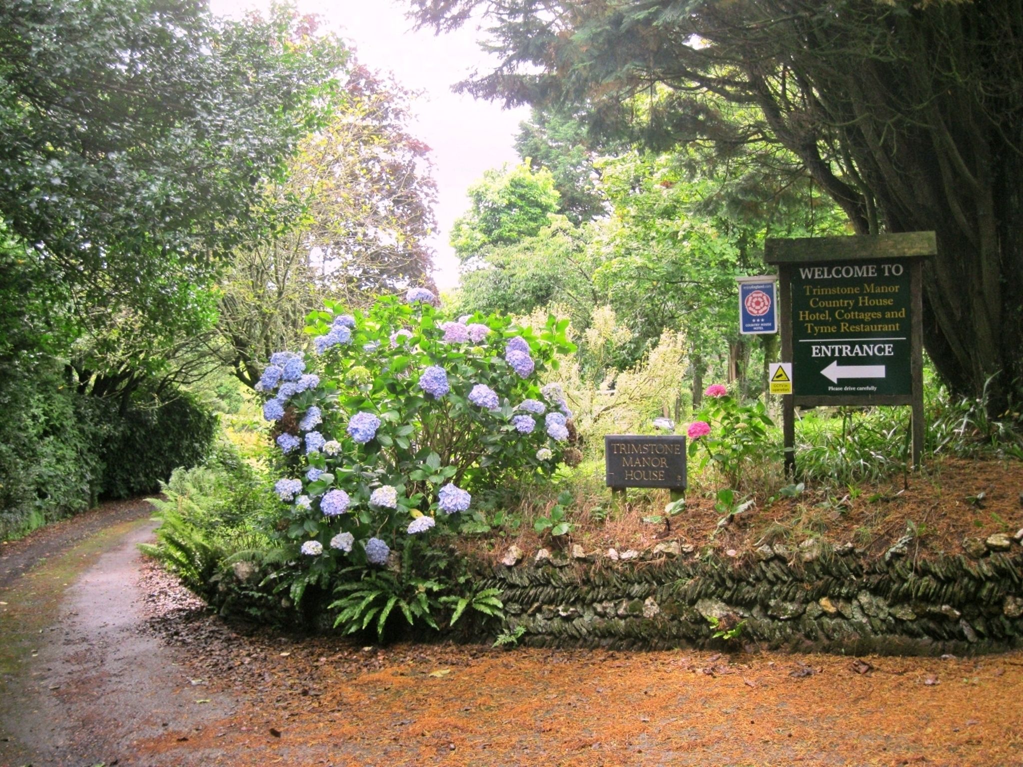 A sign welcoming visitors to Trimstone Manor House, indicating the entrance direction.