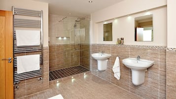 A modern bathroom with a glass-enclosed shower, two sinks, and a built-in towel rack.