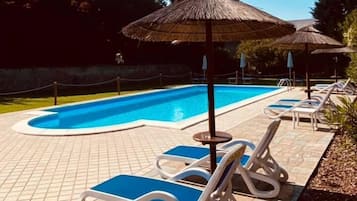 Una piscina al aire libre de temporada, sombrillas