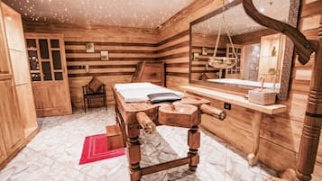 Cozy retreat with a bed, wooden bench, and chair, plus a large mirror and tiled floor.
