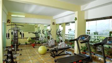 Un gimnasio con equipo de ejercicio, un espejo grande y plantas en macetas.