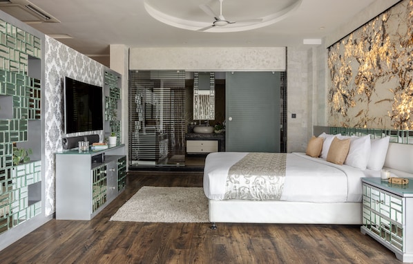Un dormitorio moderno con una cama grande, un televisor, un aparador de vidrio y un detalle decorativo en la pared.