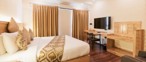 Una habitación de hotel con una cama grande, un escritorio con silla, televisión y ventilador de techo.