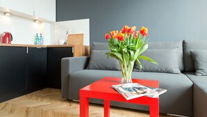 A modern living area with a grey sofa, a red table with a magazine, and a vase of tulips. - Smolna Apartments by Your Freedom (Warsaw)