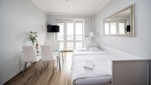A modern hotel room with a bed, a desk with chairs, a television, and a large mirror. - Smolna Apartments by Your Freedom (Warsaw)