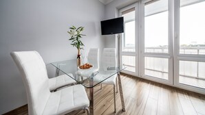 A modern room with a glass table, white chairs, a flat-screen TV, and large windows offering a view of the city. - Smolna Apartments by Your Freedom (Warsaw)