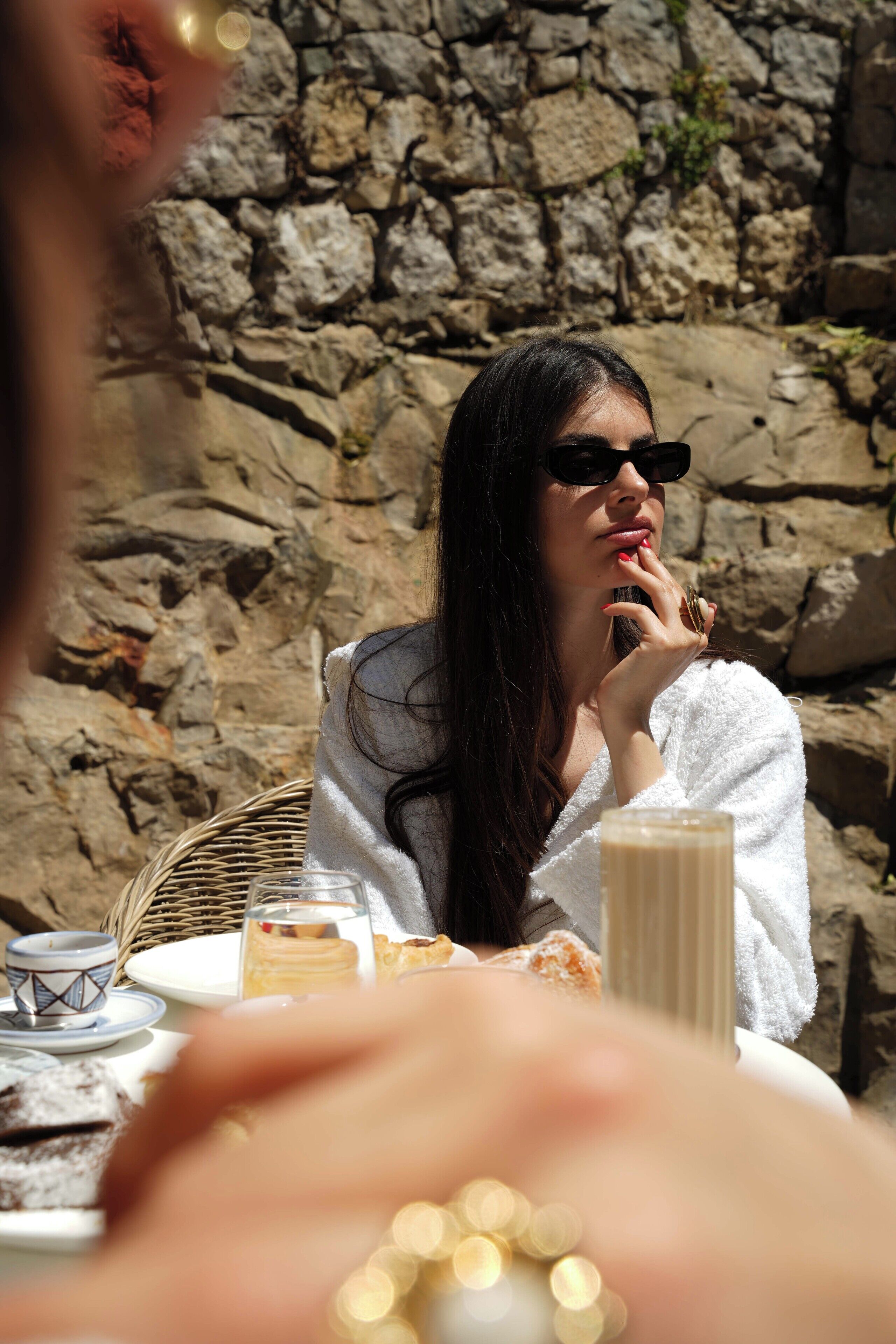A person sitting at a table with a stone wall in the background.
