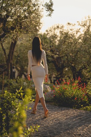 Una mujer caminando por un sendero adoquinado rodeado de vegetación y árboles.