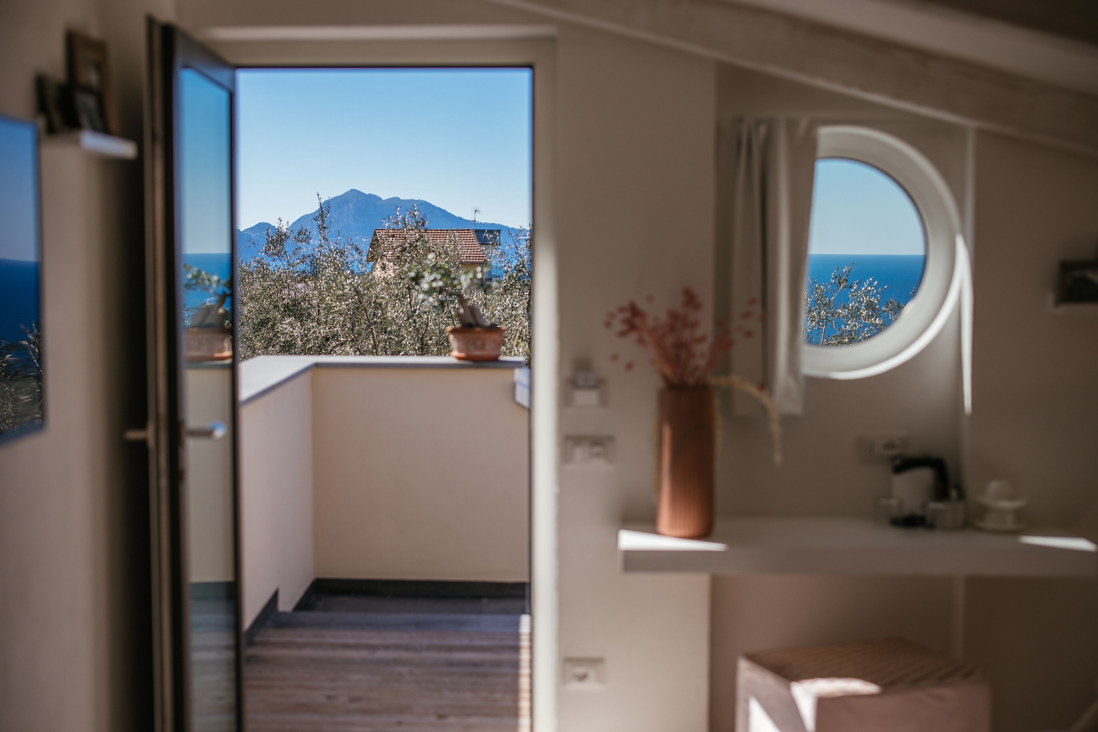 Une chambre avec vue sur la mer et les montagnes, visible par une fenêtre.