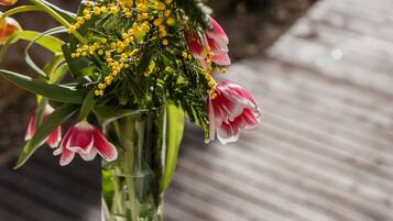 A round white table with a glass of white wine, a book, and a vase of flowers.