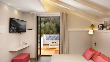 Een slaapkamer met een bed, een rode bank, een televisie en een balkon met een tafel en planten.