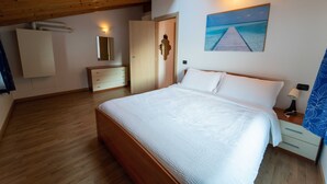 Un dormitorio con una cama de madera, una mesita de noche, un aparador, un espejo y un cuadro de un muelle.