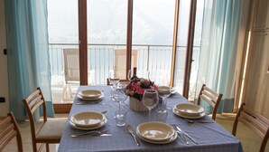 Una mesa de comedor dispuesta con platos, cubiertos y vasos, con vistas a un paisaje pintoresco.