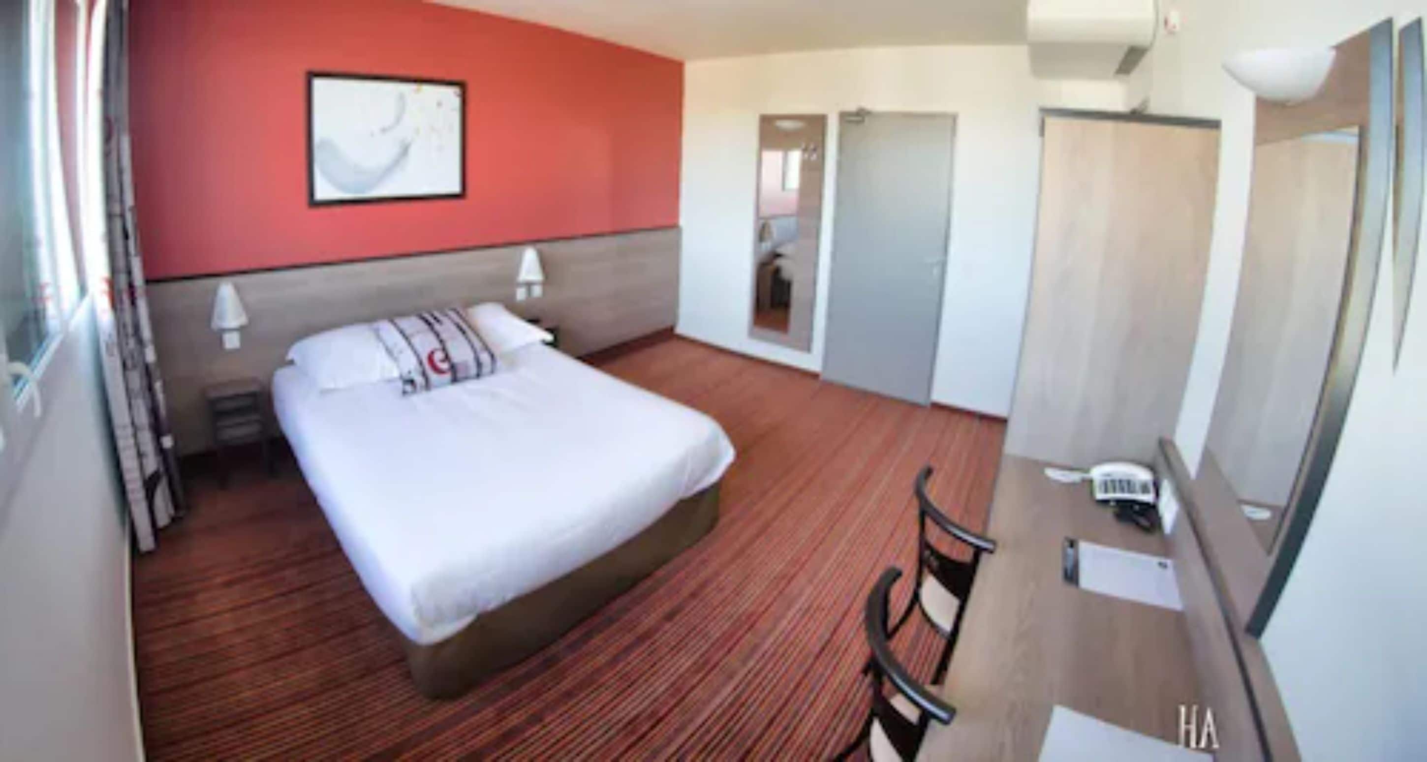 A hotel room with a bed, a desk, and a chair.