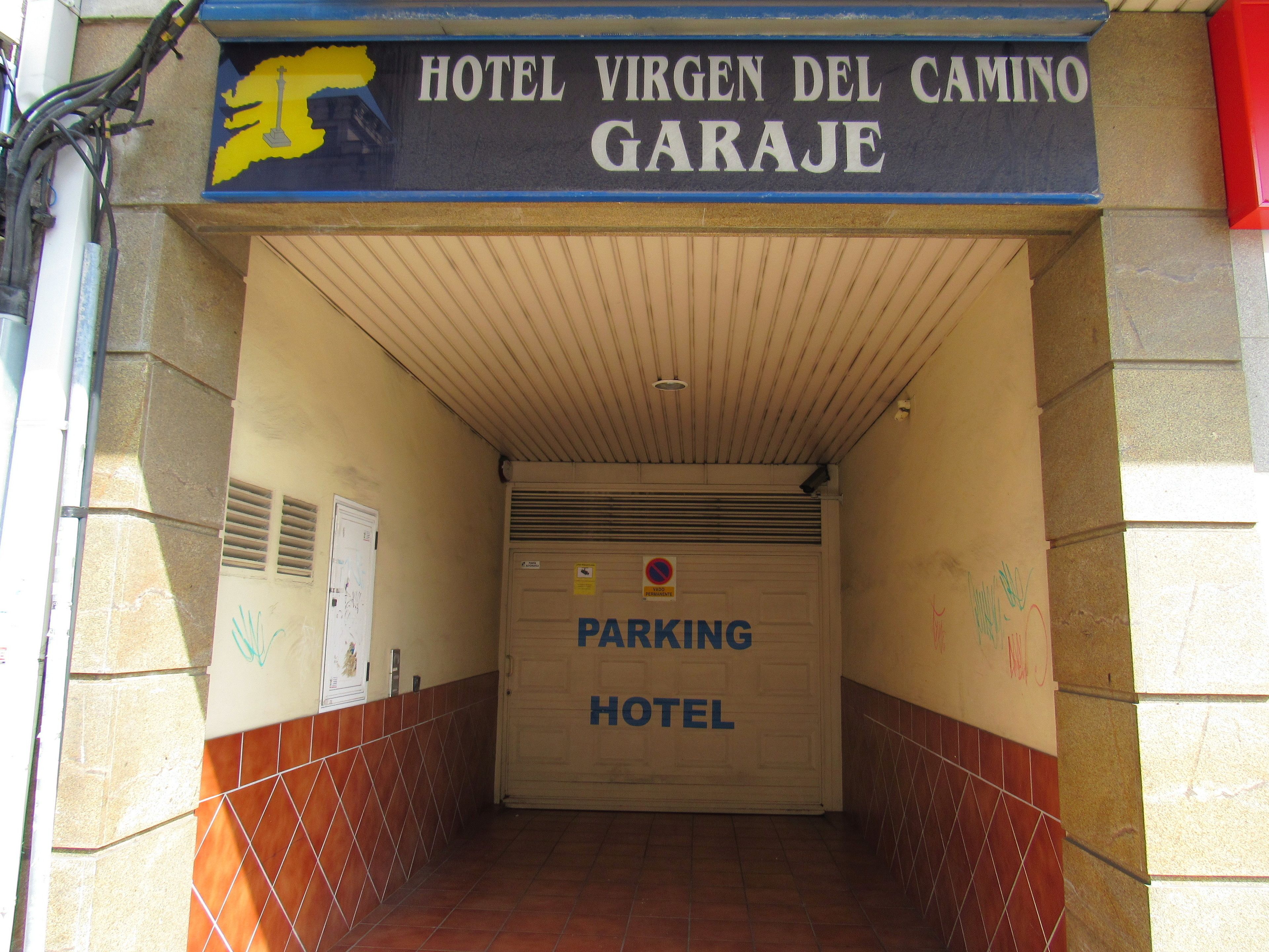 The entrance to Hotel Virgén del Camino Garage with a tiled floor and a closed garage door.