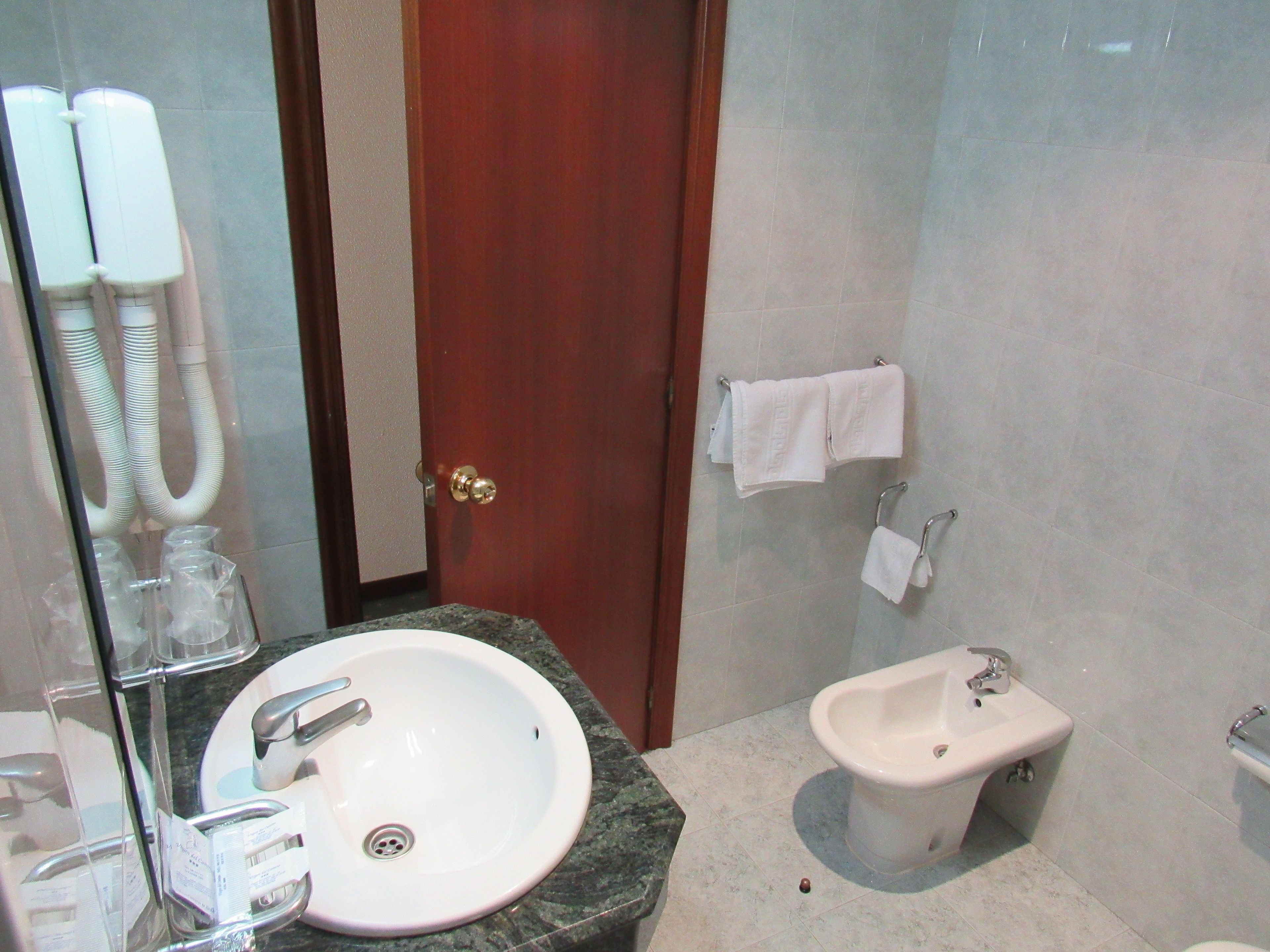 A bathroom with a sink, bidet, and towel rack.