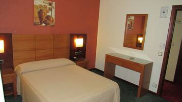 Una habitación de hotel con una cama, mesitas de noche, un espejo y un pequeño escritorio.