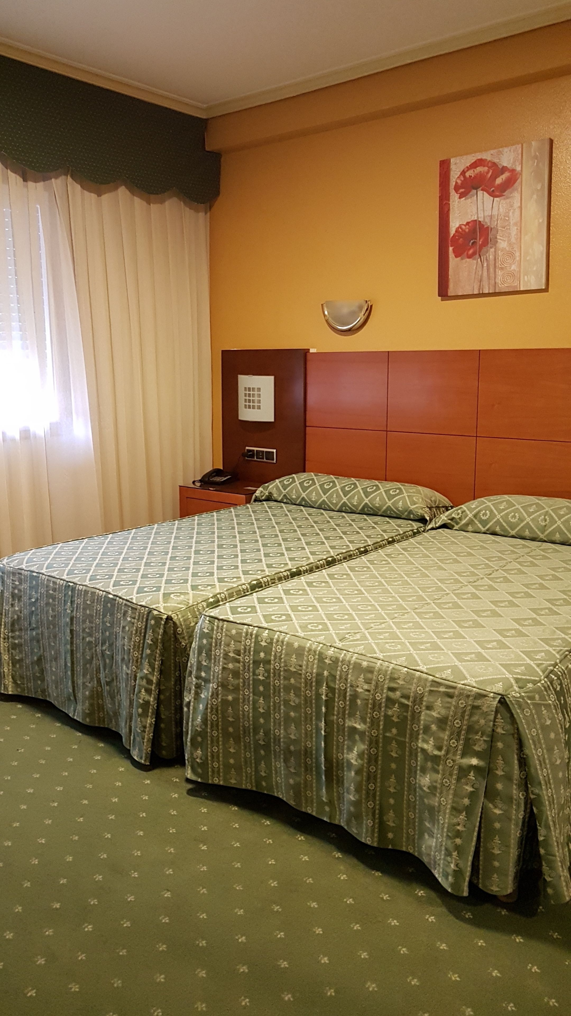 A hotel room with two beds, a nightstand, a telephone, and a painting on the wall.
