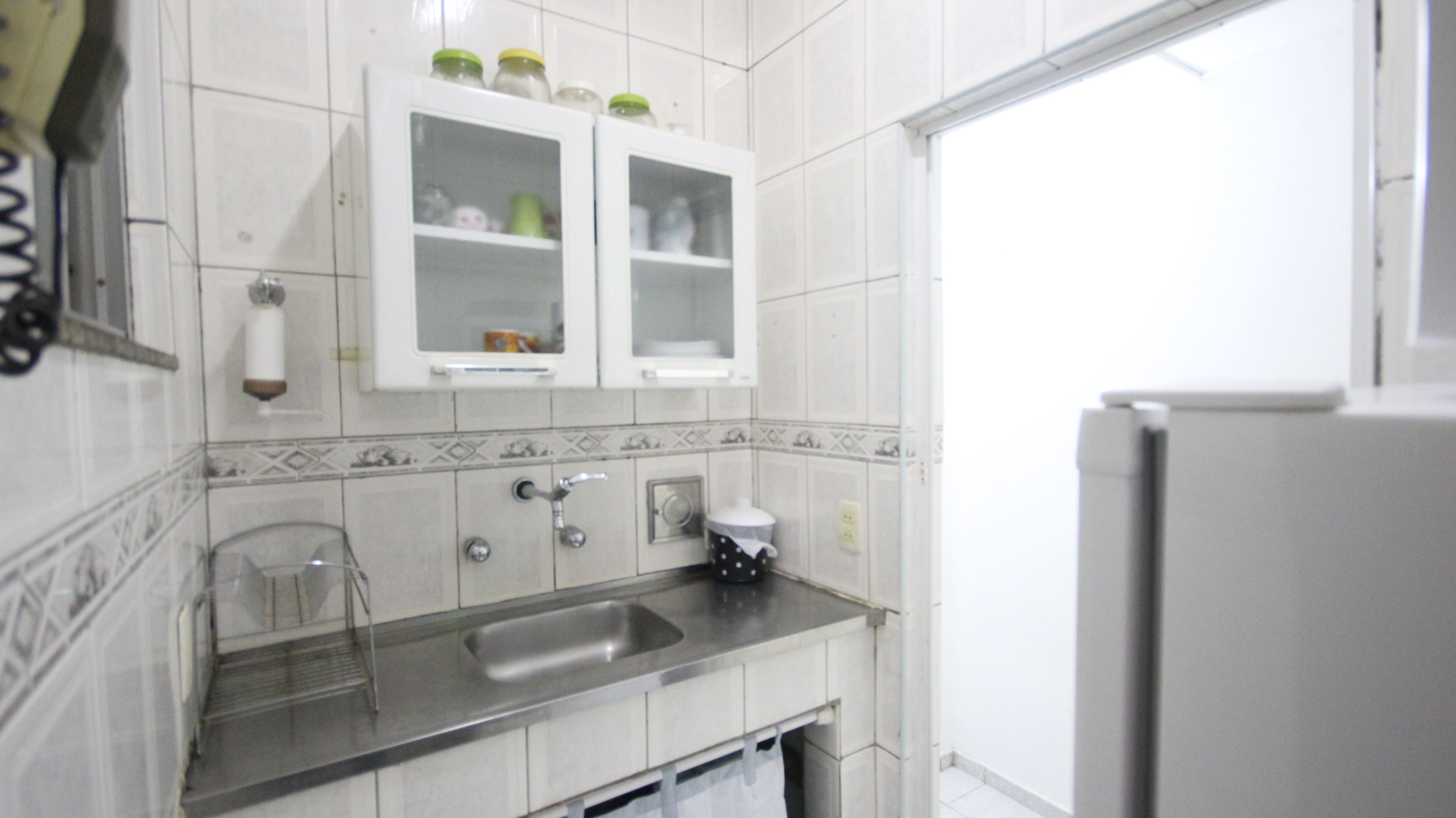 A kitchen with white cabinets, a stainless steel sink, and a refrigerator.