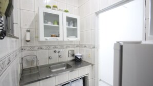Una cocina con armarios blancos, un lavamanos de acero inoxidable y un refrigerador.