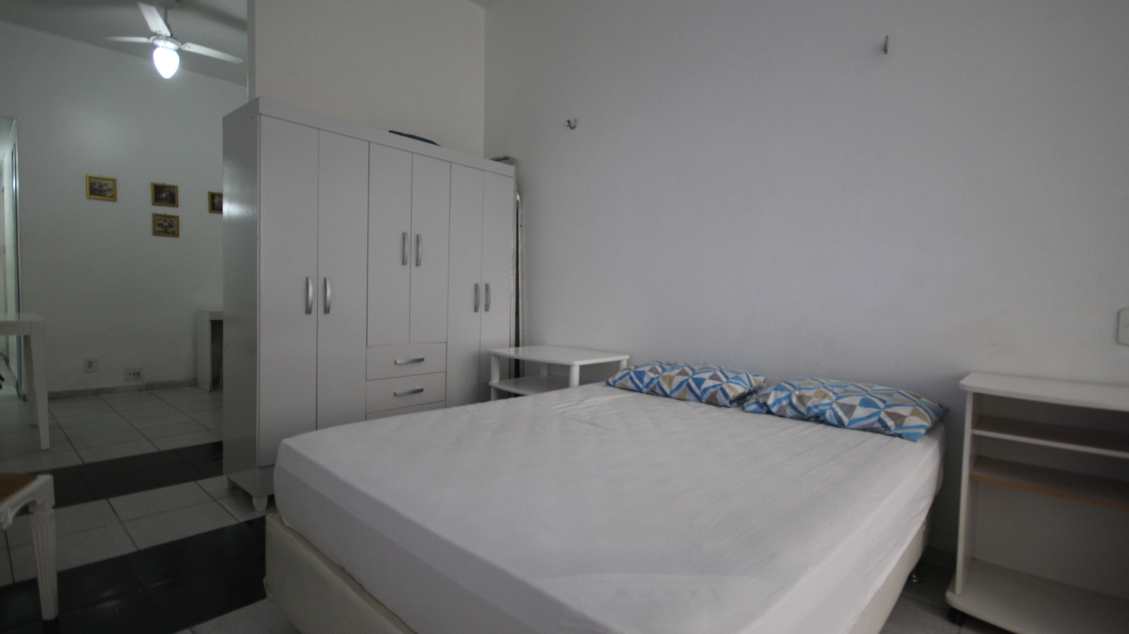 A bedroom with a bed, a wardrobe, a small table, and a chair.
