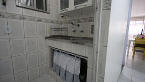 Una cocina con paredes de azulejos blancos, una encimera de acero inoxidable y un horno empotrado.