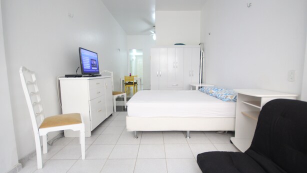 Un dormitorio con una cama, un escritorio con una computadora, una silla y un armario.