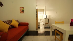 Un espacio habitable compacto con un sofá rojo, una mesa blanca y una pequeña cocina.