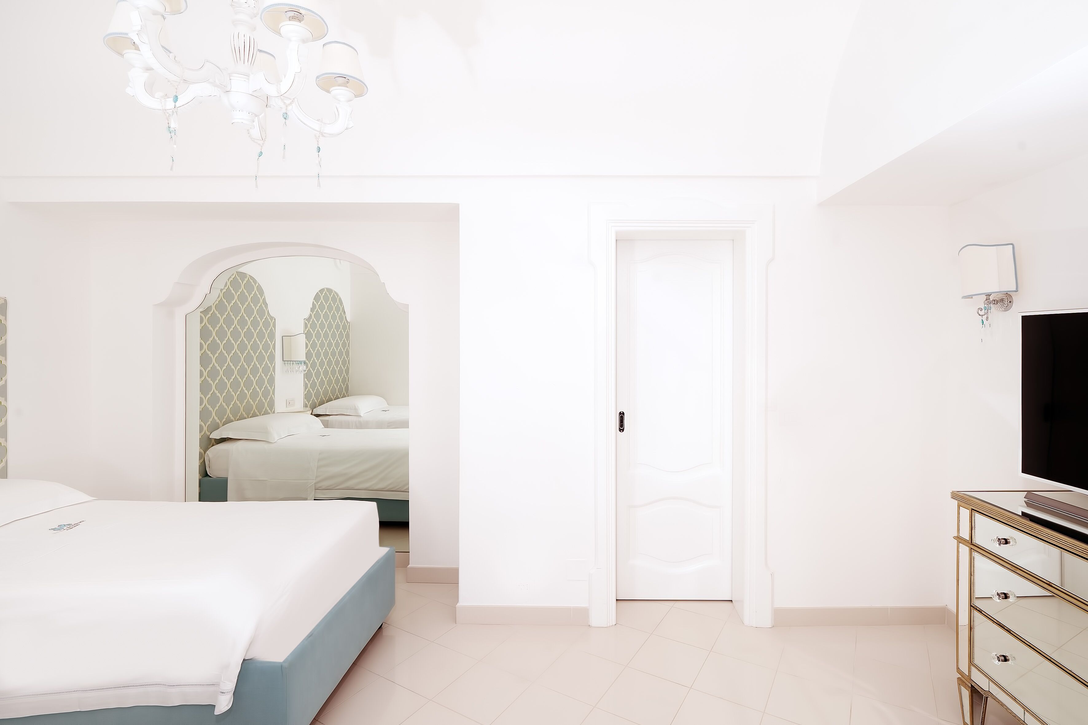 Un dormitorio con cama, cómoda, televisor y candelabro.