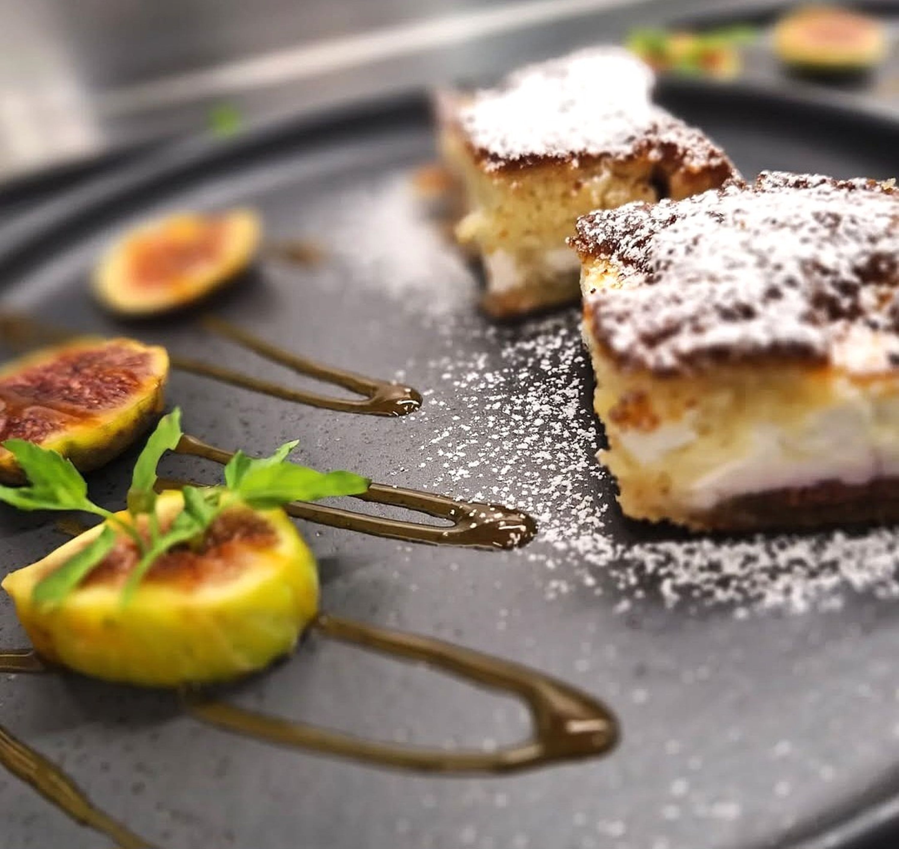 Un plato de postres con pastelería, higos y un hilo de salsa.