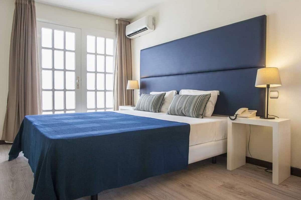Ein Hotelzimmer mit Bett, Nachttischen, Telefon und Klimaanlage.