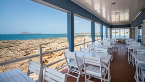 En restaurant ved stranden med udendørs siddepladser og udsigt over stranden og havet.