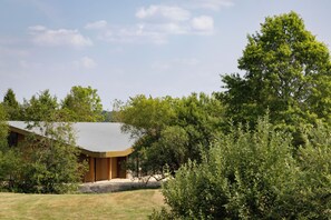 A modern house with a sloped roof, surrounded by dense greenery and trees. - Bernwood Park Hotel (Aylesbury)