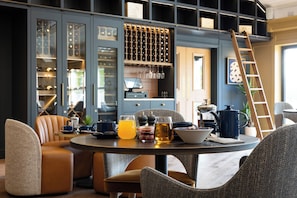 A modern dining area with a round table, leather chairs, and a wine rack in the background. - Bernwood Park Hotel (Aylesbury)