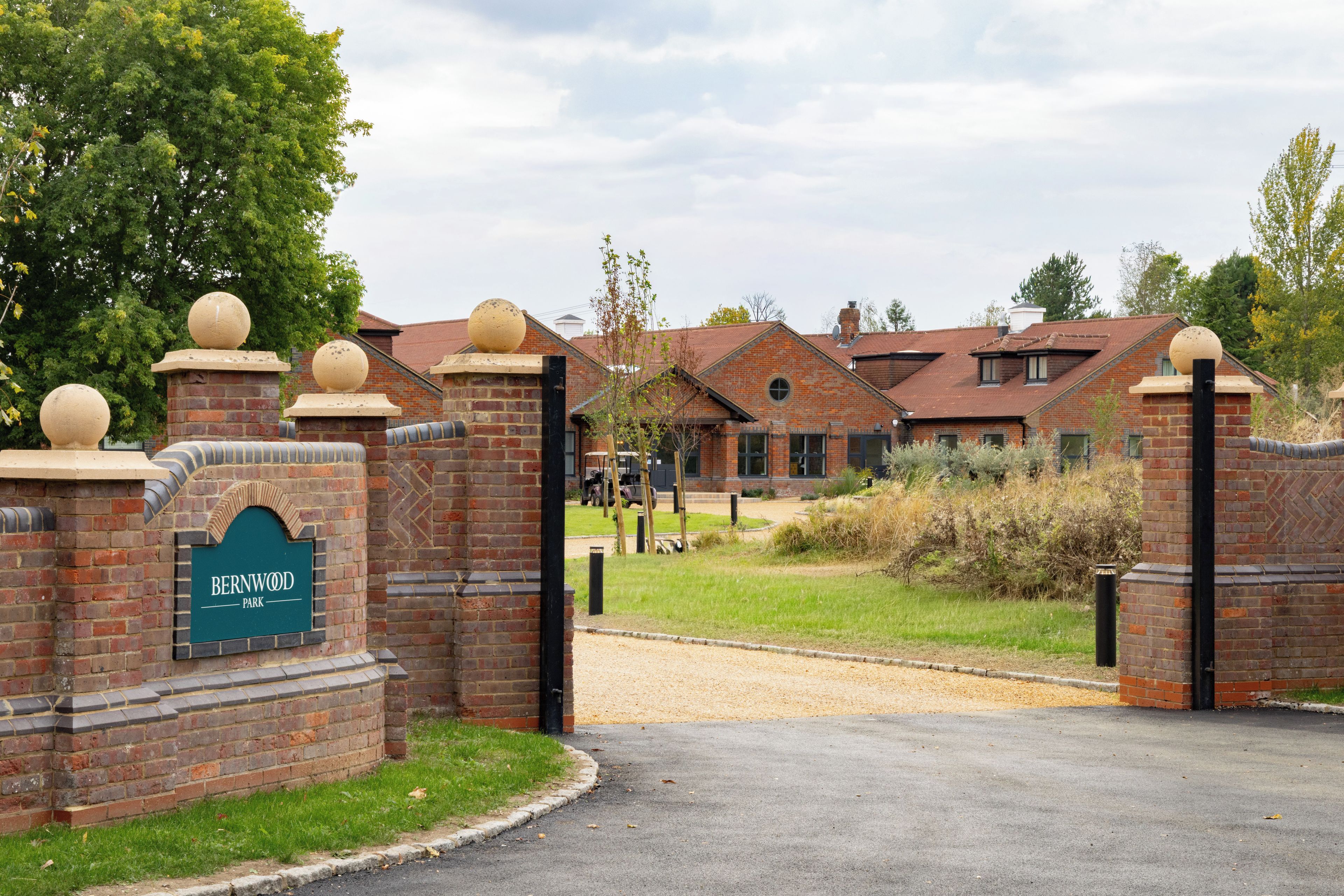 A brick building with a sign reading 'BERNWOOD PARK' and a gated entrance.