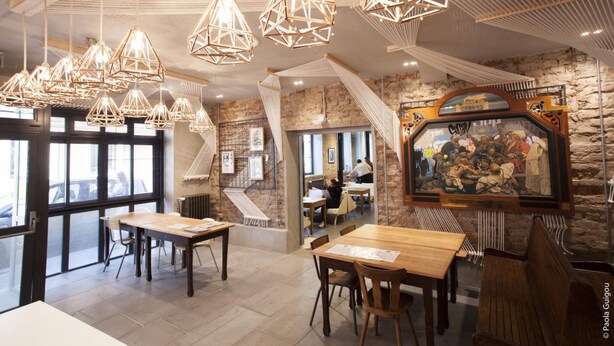 Een restaurant met houten tafels en hangende, geometrische lampen.