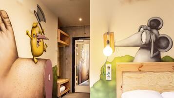 Una habitación con cabecera de madera, cama, lámpara de pared y un mural de un pájaro sosteniendo un hacha.
