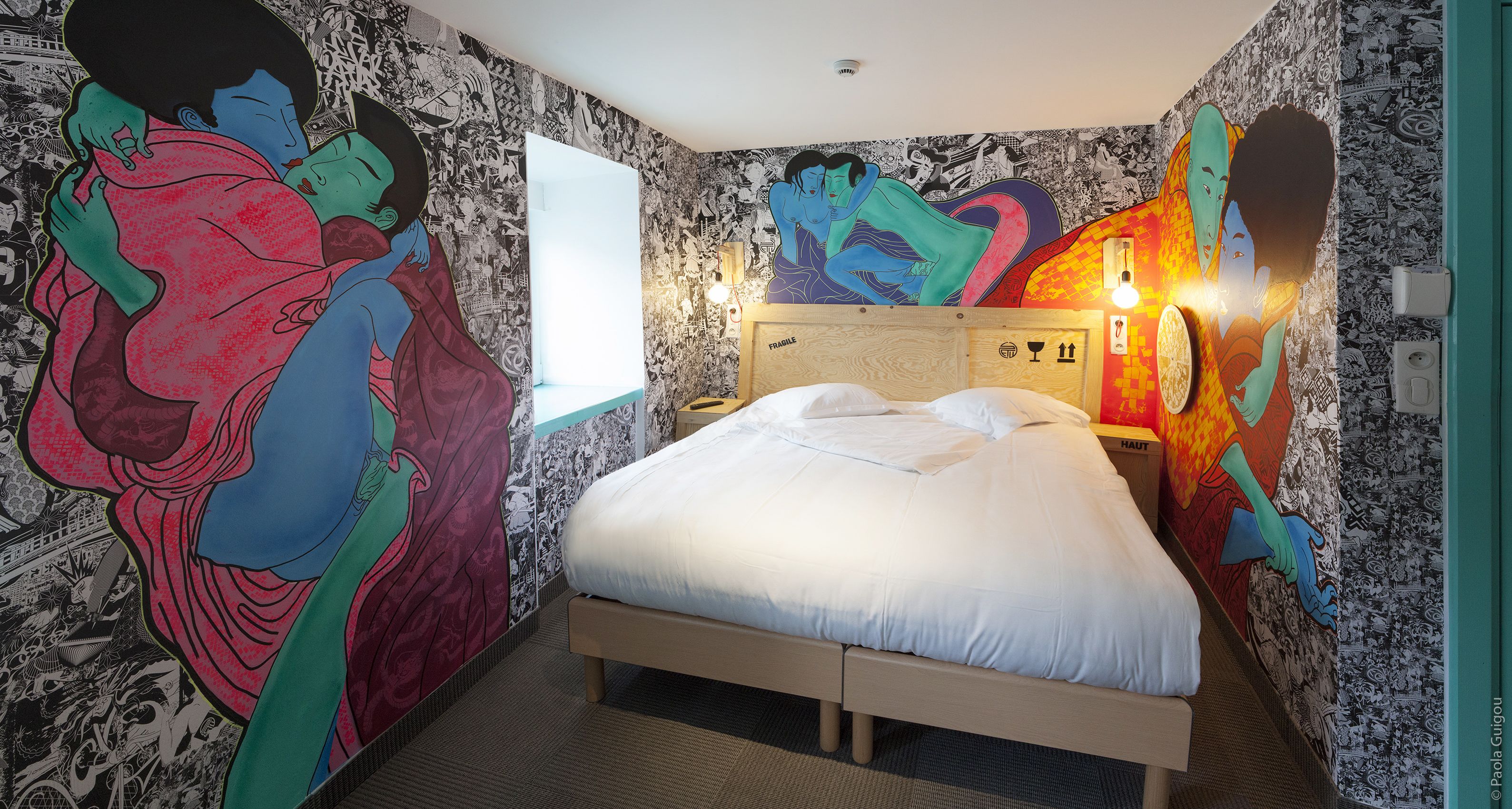 A bedroom with a large bed, a wooden headboard, and a wall mural.