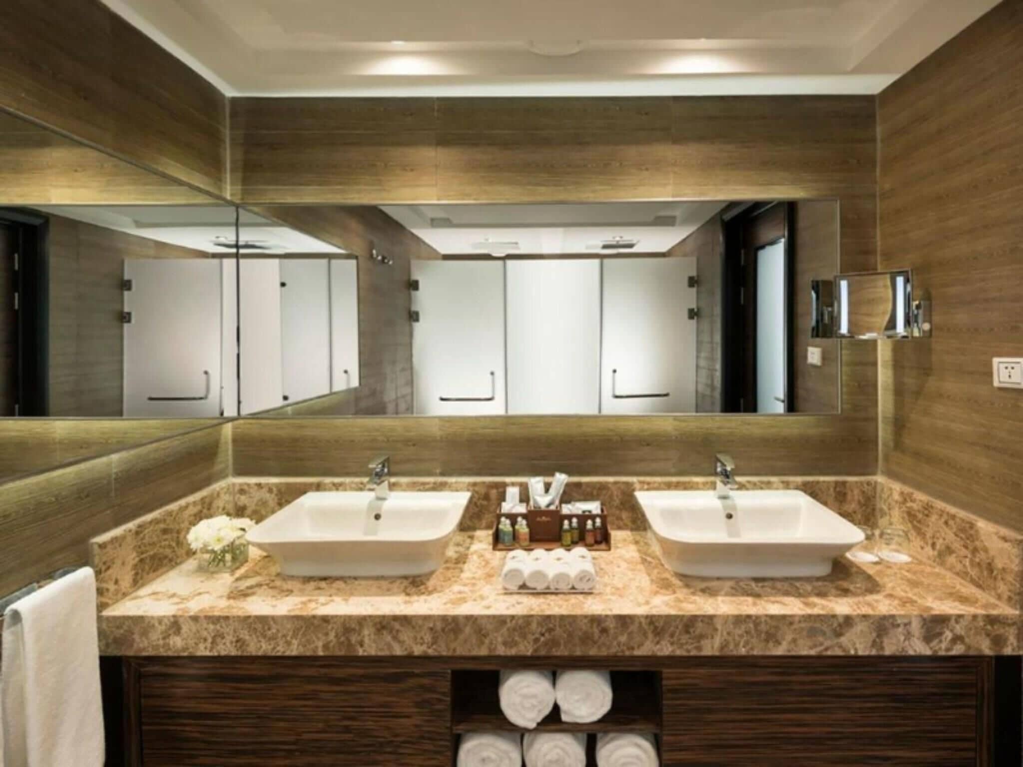 A modern bathroom with two sinks, a large mirror, and a towel rack.