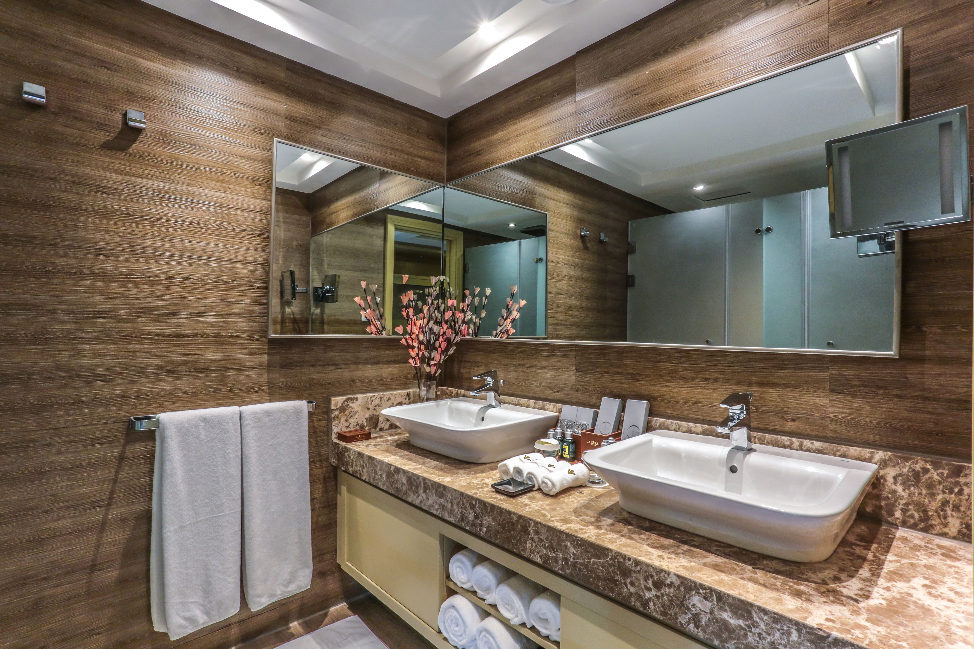 Une salle de bain moderne avec deux lavabos, un grand miroir et des panneaux muraux en bois.