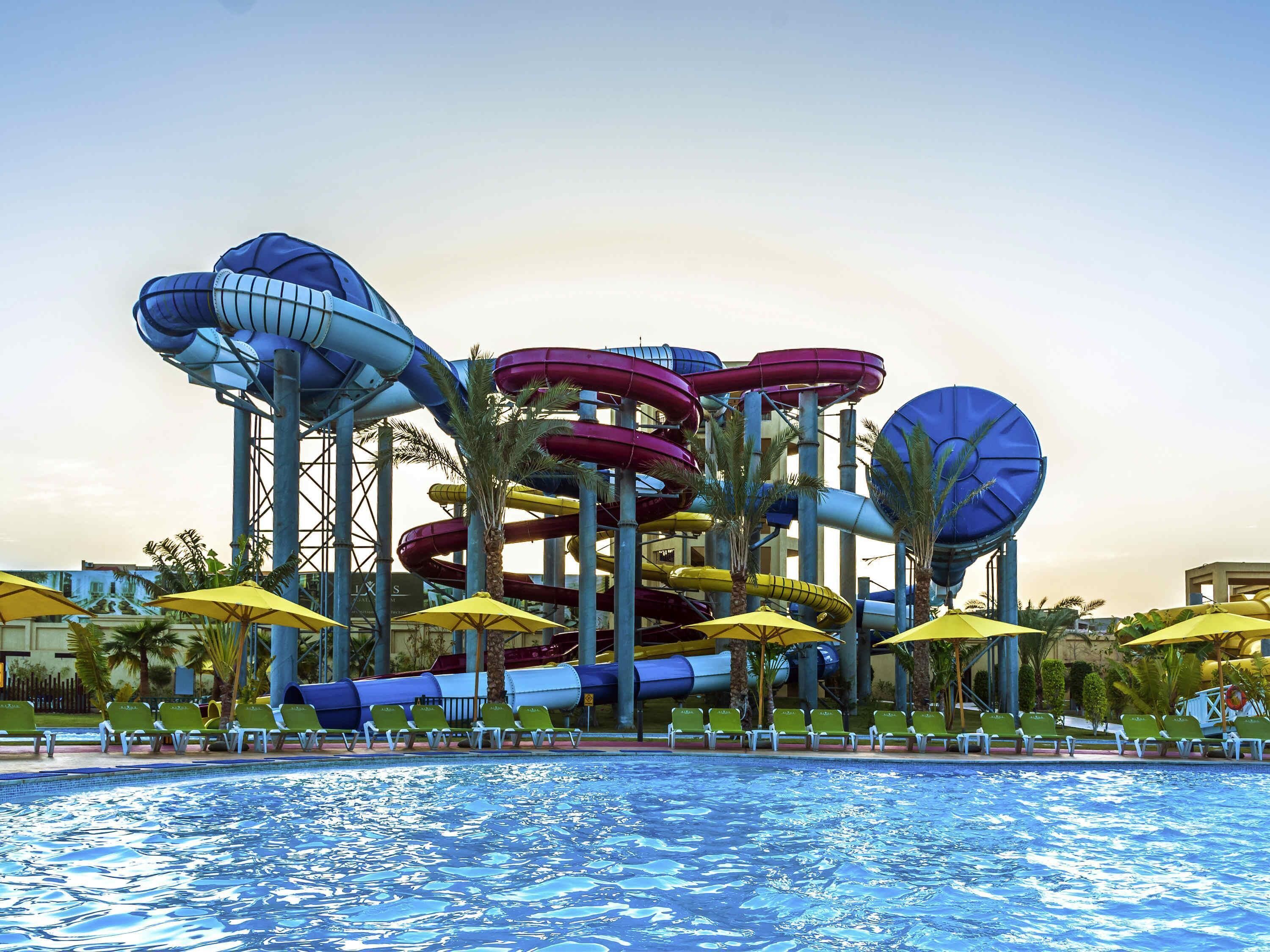 A water park with multiple water slides and a pool area with sun loungers.