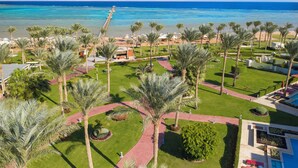 A resort with a beach view, palm trees, and a clear sky. - Rixos Premium Seagate (Sharm El Sheikh)