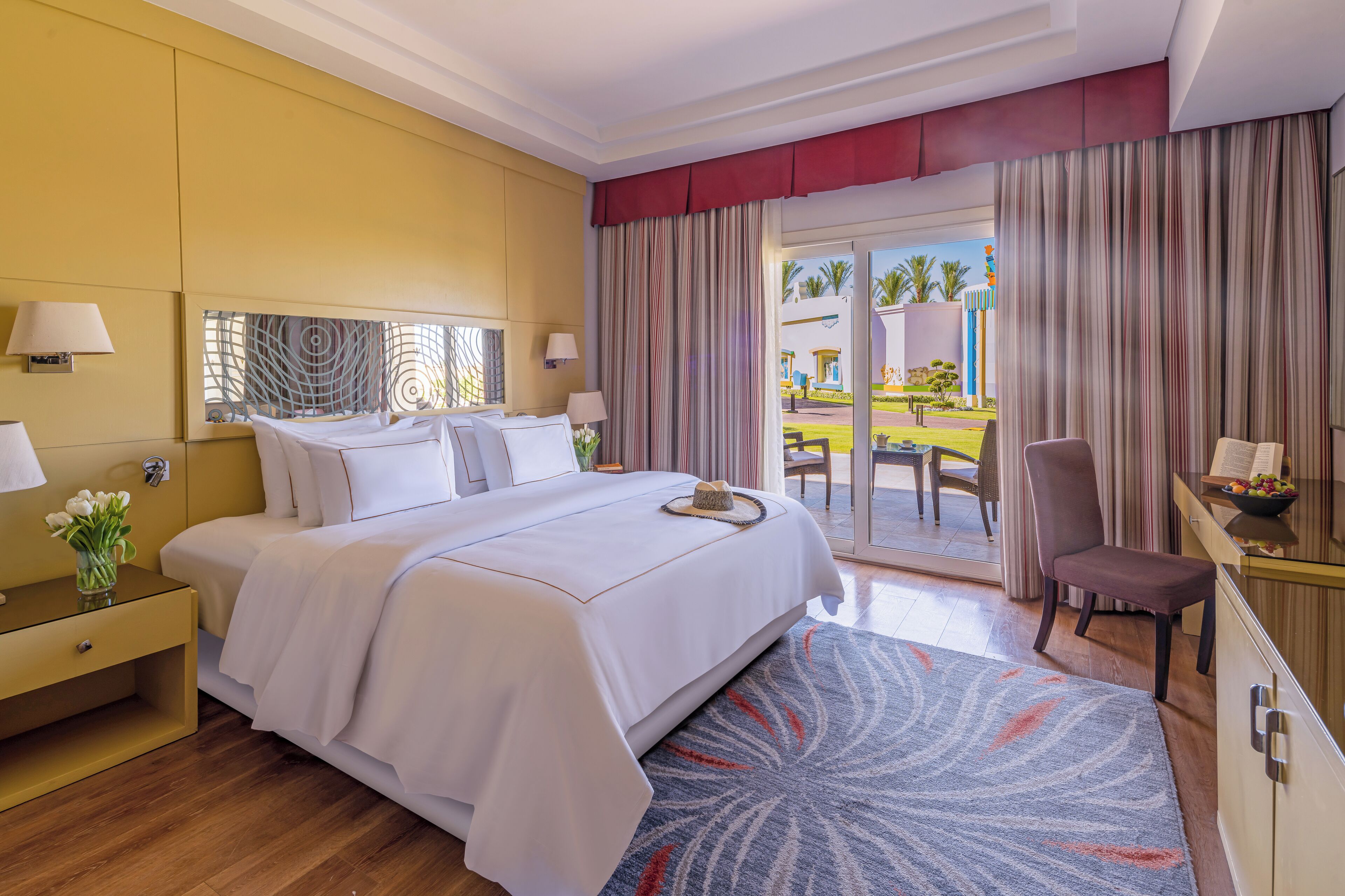 Een hotelkamer met een bed, nachtkastjes, een bureau, een stoel en uitzicht op het buitengebied.