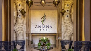 A reception area with a marble wall, a logo for 'ANJANA SPA', and a reception desk with chairs and a table. - Rixos Premium Seagate (Sharm El Sheikh)
