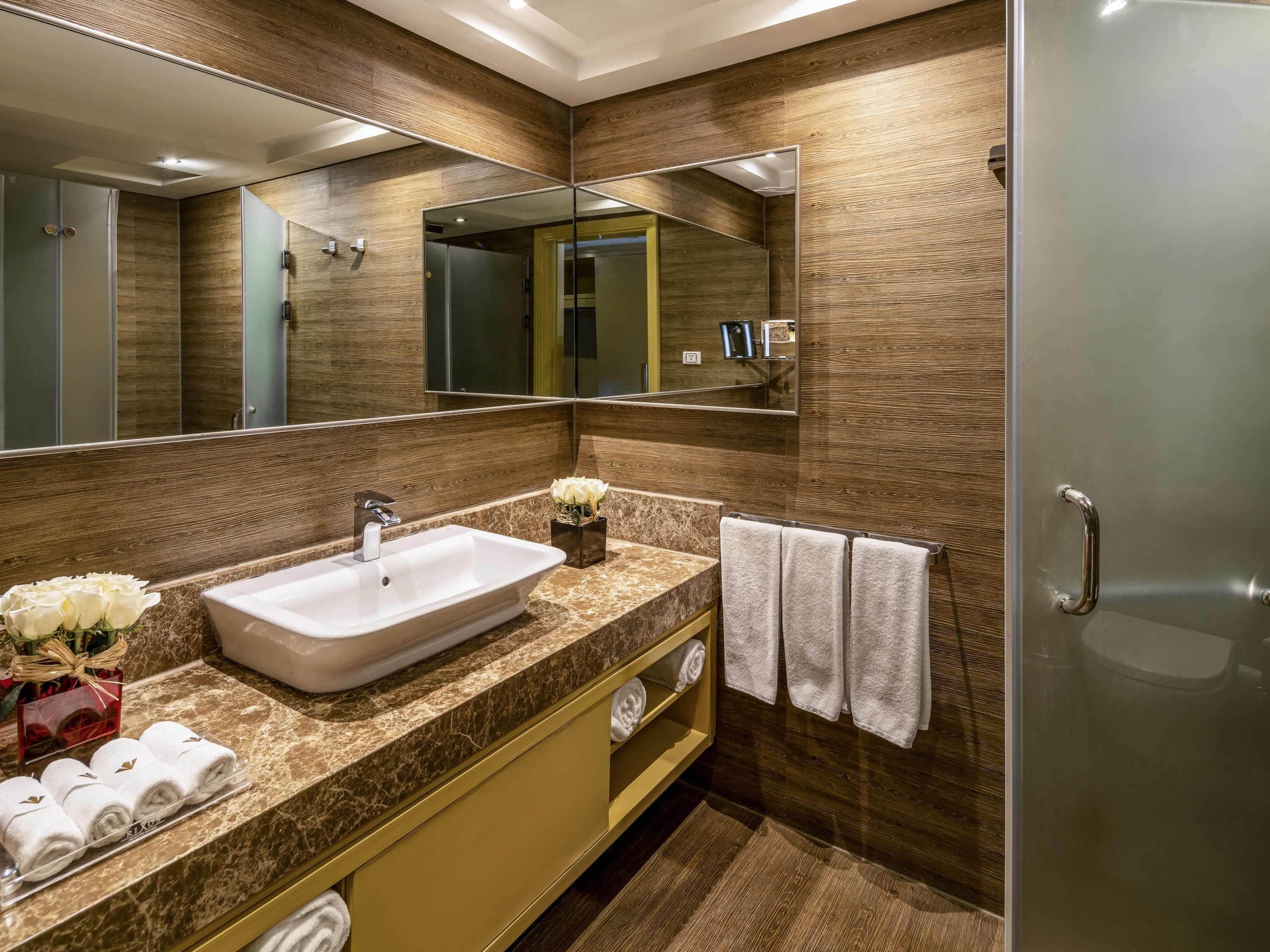 A modern bathroom with a large mirror, a sink, and a shower.