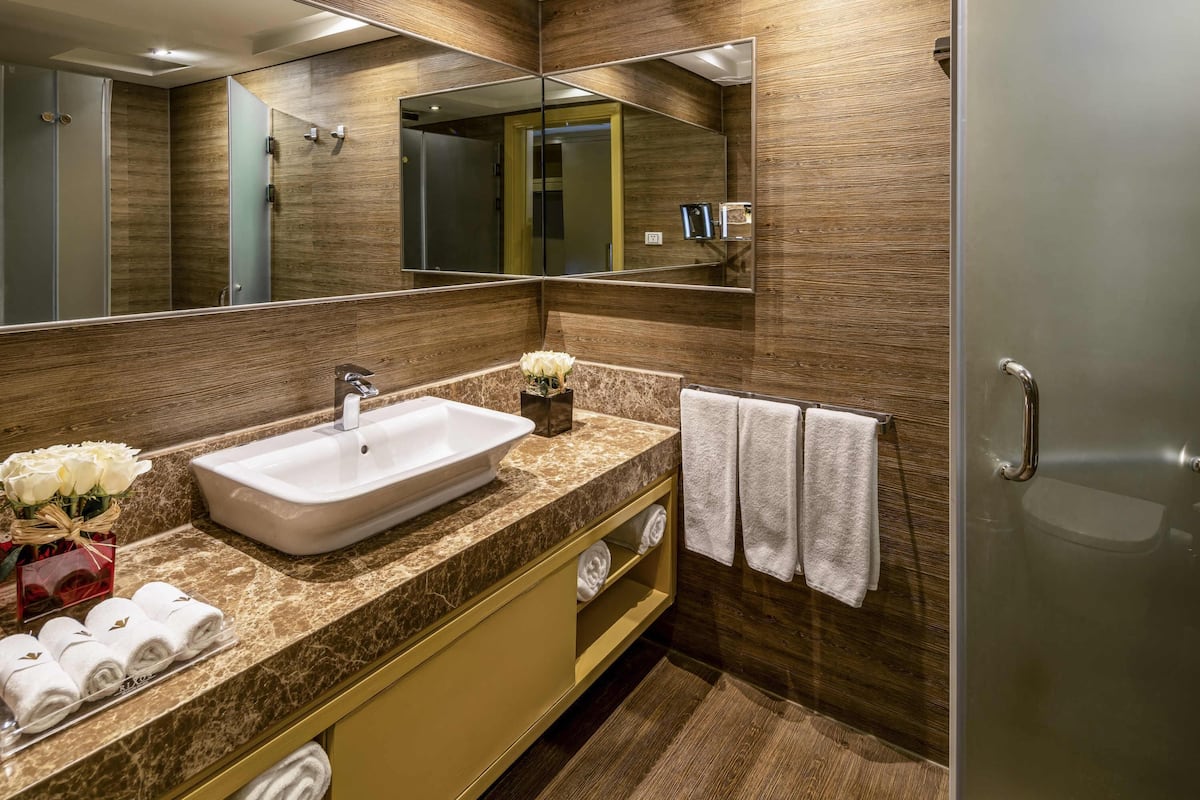 A modern bathroom with a large mirror, a sink, and a shower.