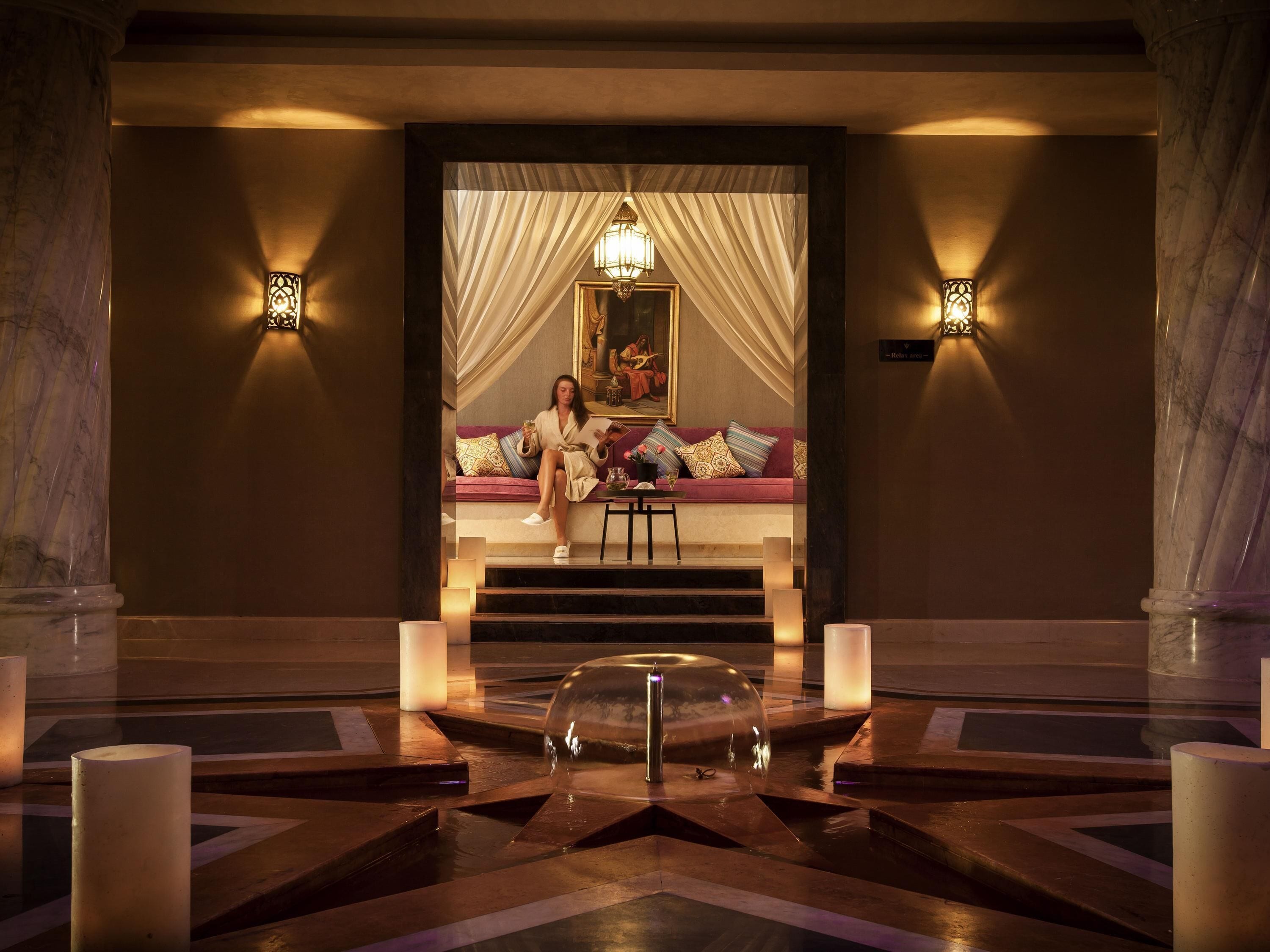 A luxurious lobby with marble columns, a grand staircase, and a seating area with a painting.