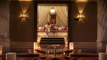 A luxurious lobby with marble columns, a grand staircase, and a seating area with a painting.