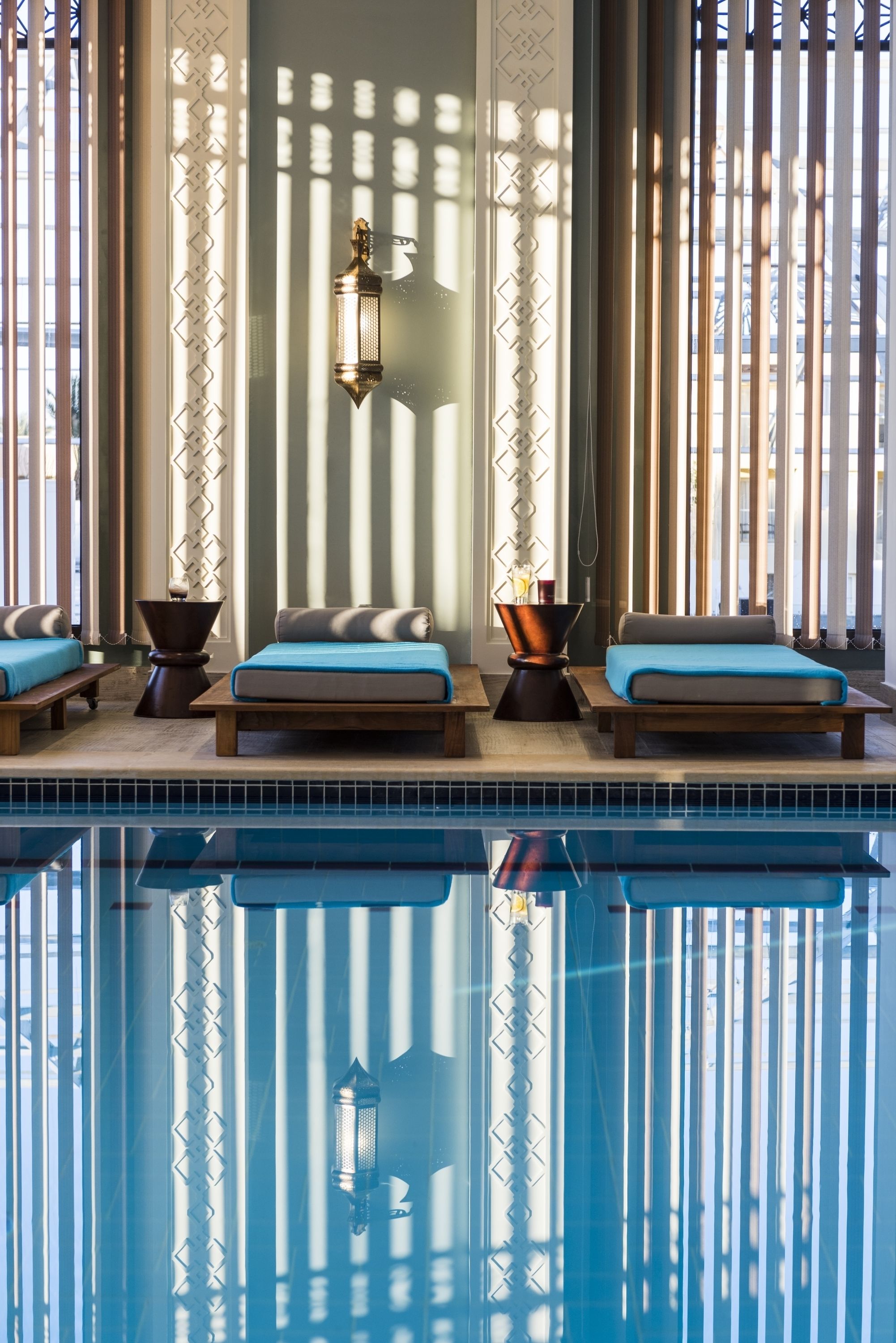Un área junto a la piscina con sillones de descanso, un farol y paneles decorativos.